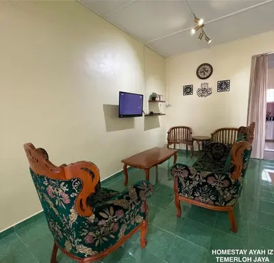 a living room with chairs and a tv and a table at Homestay Ayah Iz Temerloh Jaya in Gua Sai