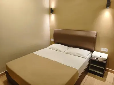 a small bedroom with a bed with a brown headboard at The Pines Hotel in Tanah Rata