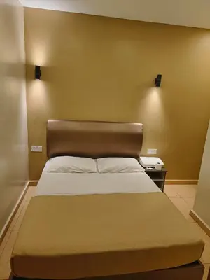 a bedroom with a large bed with a brown headboard at The Pines Hotel in Tanah Rata