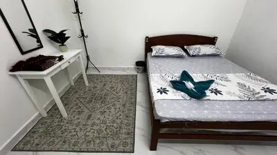 a bedroom with a bed and a nightstand and a table at D'Simpang Homestay in Sungai Petani