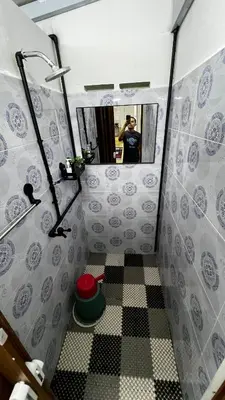 a man taking a picture of a bathroom with a mirror at D'Simpang Homestay in Sungai Petani
