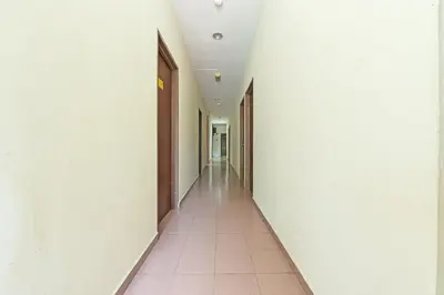 an empty corridor in an office building with white walls at SPOT ON 91178 Motel Impian in Kampong Telok Batu