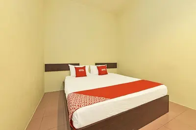a bedroom with a large bed with red pillows at SPOT ON 91178 Motel Impian in Kampong Telok Batu