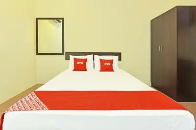 a bedroom with a large bed with two red pillows at SPOT ON 91178 Motel Impian in Kampong Telok Batu