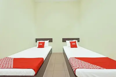 two beds in a room with red and white pillows at SPOT ON 91178 Motel Impian in Kampong Telok Batu