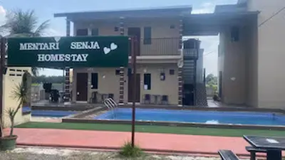a sign in front of a house with a swimming pool at Capital O 91180 Mentari Senja Homestay in Kampong Dekeh
