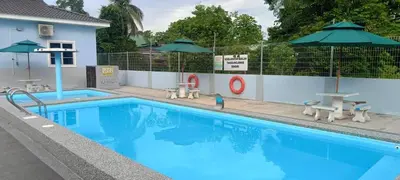 a large blue swimming pool with umbrellas and chairs at Villa Atok Opah in Teluk Intan