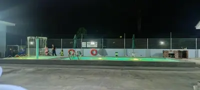 a swimming pool at night with people standing around it at Villa Atok Opah in Teluk Intan
