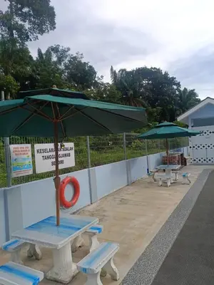 two picnic tables and umbrellas on a beach at Villa Atok Opah in Teluk Intan
