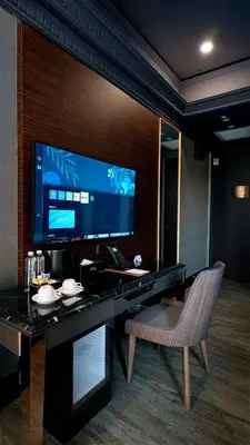 a desk with a monitor and a chair in a room at 1969 D'Kelly Hotel in Ipoh