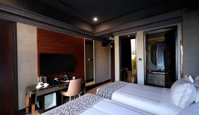 a bedroom with two beds and a desk and a television at 1969 D'Kelly Hotel in Ipoh