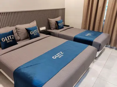 three beds in a hotel room with blue and gray at Glitz Hotel in Brinchang