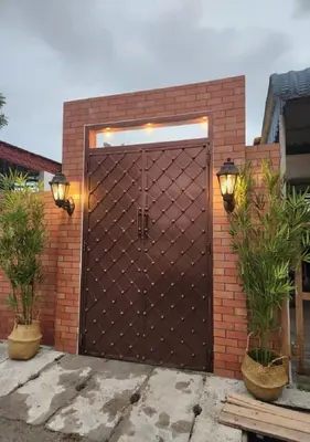 a large brown door with two potted plants at Sun Rimba Home by Ipoh Maju Stay in Ipoh