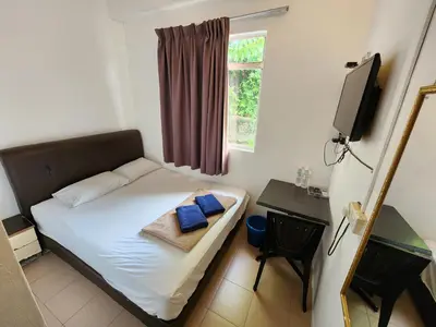 a small bedroom with a bed and a window at Rasa Motel at Batu Ferringhi in Batu Ferringhi