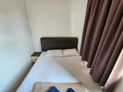 a small bed in a room with red curtains at Rasa Motel at Batu Ferringhi in Batu Ferringhi