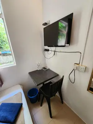 a room with a small table and a tv on the wall at Rasa Motel at Batu Ferringhi in Batu Ferringhi