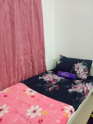 a bed with a black and pink comforter with flowers on it at Auliya Homestay in Gua Sai