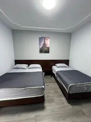 a bedroom with two beds and a painting on the wall at Eiffel Villa Homestay Melaka in Gua Sai