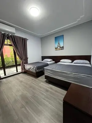 a bedroom with two beds and a large window at Eiffel Villa Homestay Melaka in Gua Sai