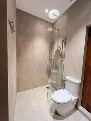 a bathroom with a toilet and a glass shower at Shinju Villa with Jacuzzi Pool in Jelutong