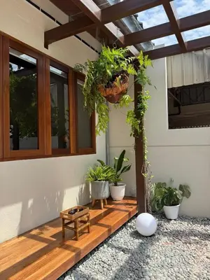 a porch with potted plants and a wooden floor at Shinju Villa with Jacuzzi Pool in Jelutong