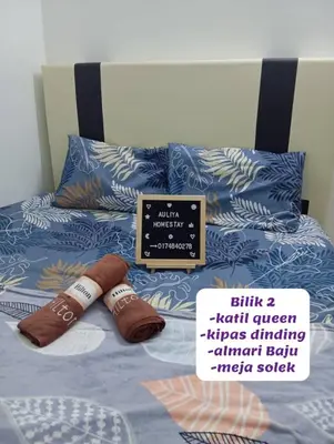 a bed with two brown slippers and a sign on it at Auliya Homestay in Gua Sai