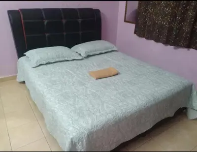 a bed with a blue comforter and a brown pillow at Homestay Manjoi - muslim2 in Ipoh