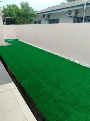 a fake green lawn in front of a white fence at Cream Roof Homestay in Gua Sai