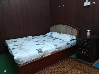 a bed with a white comforter and a night stand at Homestay Melati in Ipoh