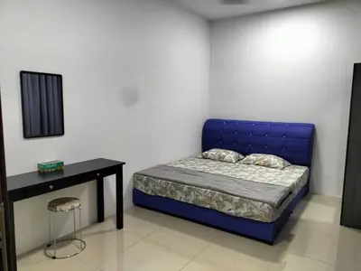 a bedroom with a blue bed and a table at Yatie Homestay in Gua Musang
