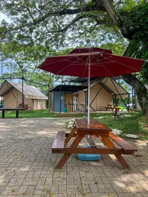 a picnic table with an umbrella next to a building at Glamping at Xscape Tambun in Ipoh