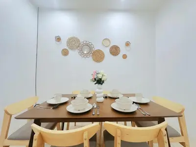 a wooden table with chairs and plates and flowers on it at BM Alma AutoCity Aeonjusco in Bukit Mertajam