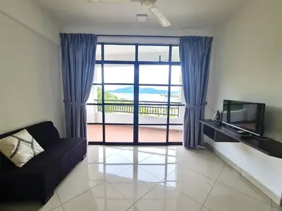 a living room with a couch and a sliding glass door at Marina Teluk Batik by Manhattan Group in Lumut