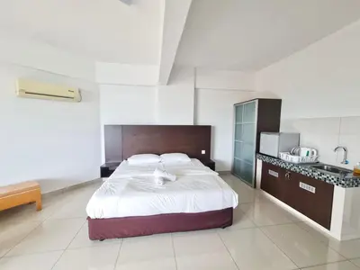 a bedroom with a large bed and a kitchen at Marina Teluk Batik by Manhattan Group in Lumut