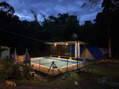 a house with a swimming pool at night at Camping River View in Gua Sai