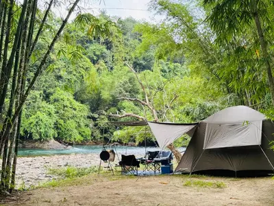 a tent in the woods next to a river at Camping River View in Gua Sai