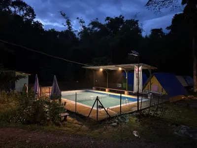 a swimming pool in a yard at night at Camping River View in Gua Sai