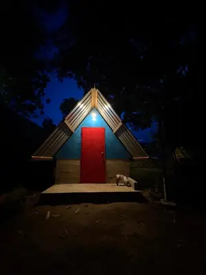 a dog sitting in front of a red door at Camping River View in Gua Sai