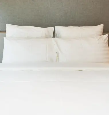 an unmade bed with white sheets and pillows at CozyStay Rooftop Sky Pool Sea &Bridge View Luxury 9pax in Bayan Lepas