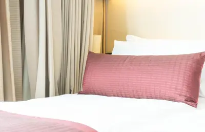 a bed with a red pillow next to a window at CozyStay Rooftop Sky Pool Sea &Bridge View Luxury 9pax in Bayan Lepas