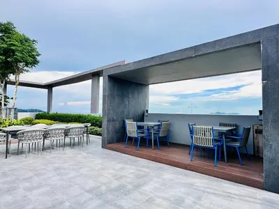 a patio with tables and chairs on a deck at Luxe Seaview Rooftop Pool Airport bayan lepas in Bayan Lepas