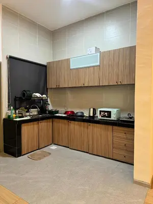 a kitchen with wooden cabinets and a large screen at AYAAN Nova PingPong House Free Parking in Tanah Rata