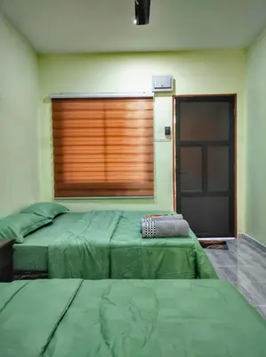 two green beds in a room with a window at Inapan Tepi Sawah
