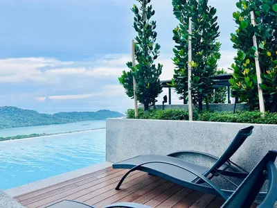 a pair of chairs sitting on a deck next to a pool at Premium Comfort Rooftop View bayan lepas airport 9pax in Bayan Lepas