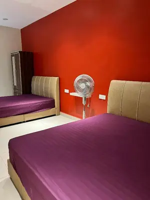 a bedroom with two beds with purple sheets and a fan at Alma Sweet Home in Bukit Mertajam