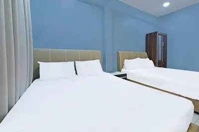 two white beds in a room with blue walls at Alma Sweet Home in Bukit Mertajam