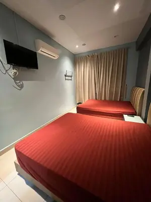two beds in a hotel room with red sheets at Alma Sweet Home in Bukit Mertajam