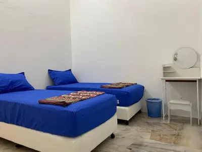 two beds in a room with blue sheets and a table at Staycation Taiping Homestay in Taiping