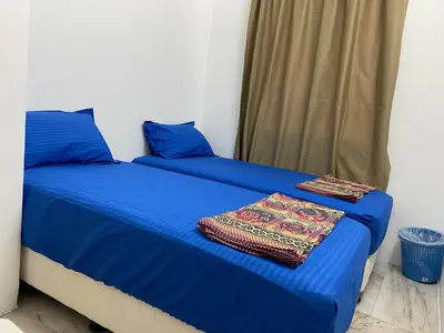 two beds in a room with blue sheets at Staycation Taiping Homestay in Taiping