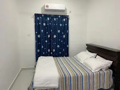 a small bed in a room with a blue curtain at Homestay Aman Berkat in Kampar